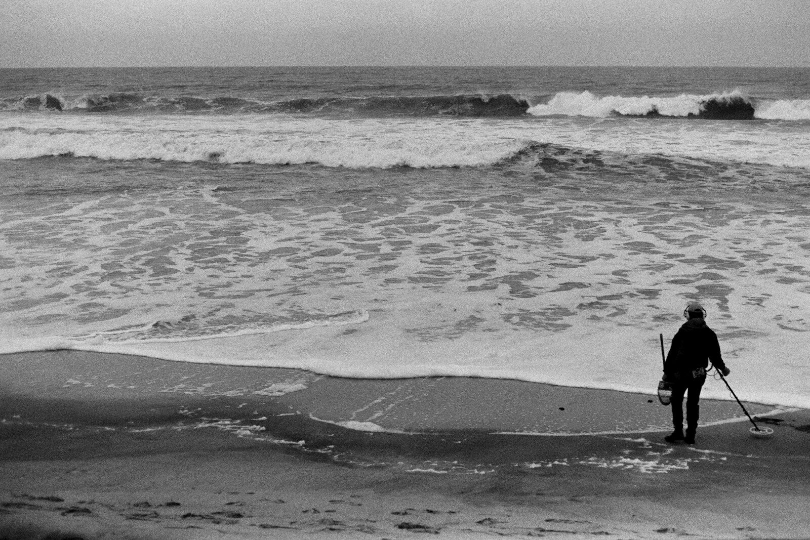 Person with tool and bucket on a beach by ocean